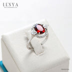 LENYA แหวนโกเมน (Garnet)  สีแดงแก่ก่ำ ช่วยปกป้องคุ้มครอง และช่วยให้สมปรารถนาในเรื่องหน้าที่การงาน การเงินและเรื่องความรัก ล้อมรอบด้วยคิวบิคเซอร์โคเนีย 22 เม็ด บนตัวเรือนเงินแท้ 925 ชุบทองคำขาว